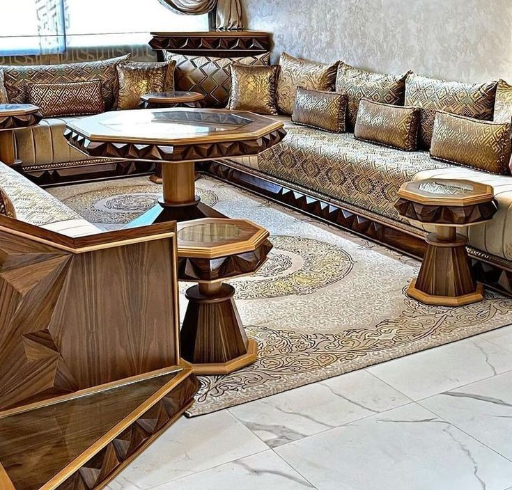 Salon marocain moderne avec banquettes en tissu beige, tables rondes en bois sculpté et tapis traditionnel.