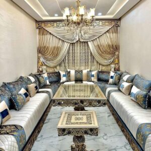 Grand salon marocain luxueux avec plafond sculpté, lustre central doré et canapés traditionnels.