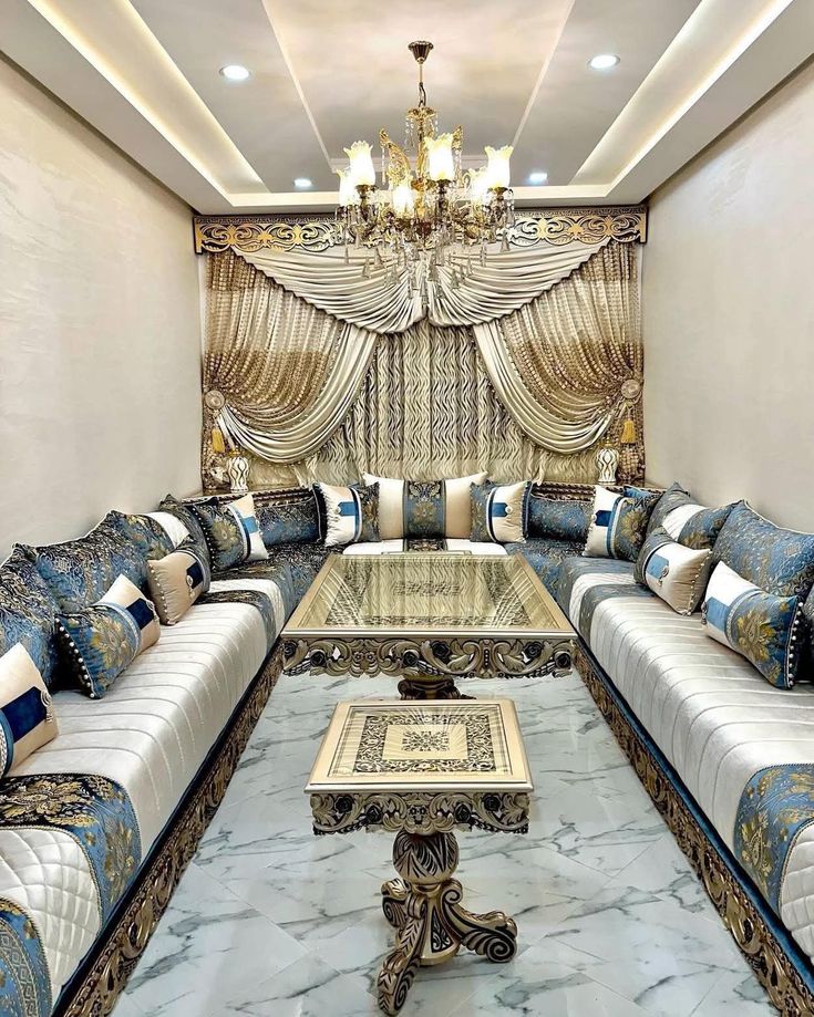 Grand salon marocain luxueux avec plafond sculpté, lustre central doré et canapés traditionnels.