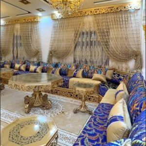 Salon marocain luxueux bleu et doré avec plafond éclairé et tables rondes sculptées.