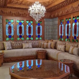 Salon marocain en bois sculpté avec vitraux colorés et lustre traditionnel.